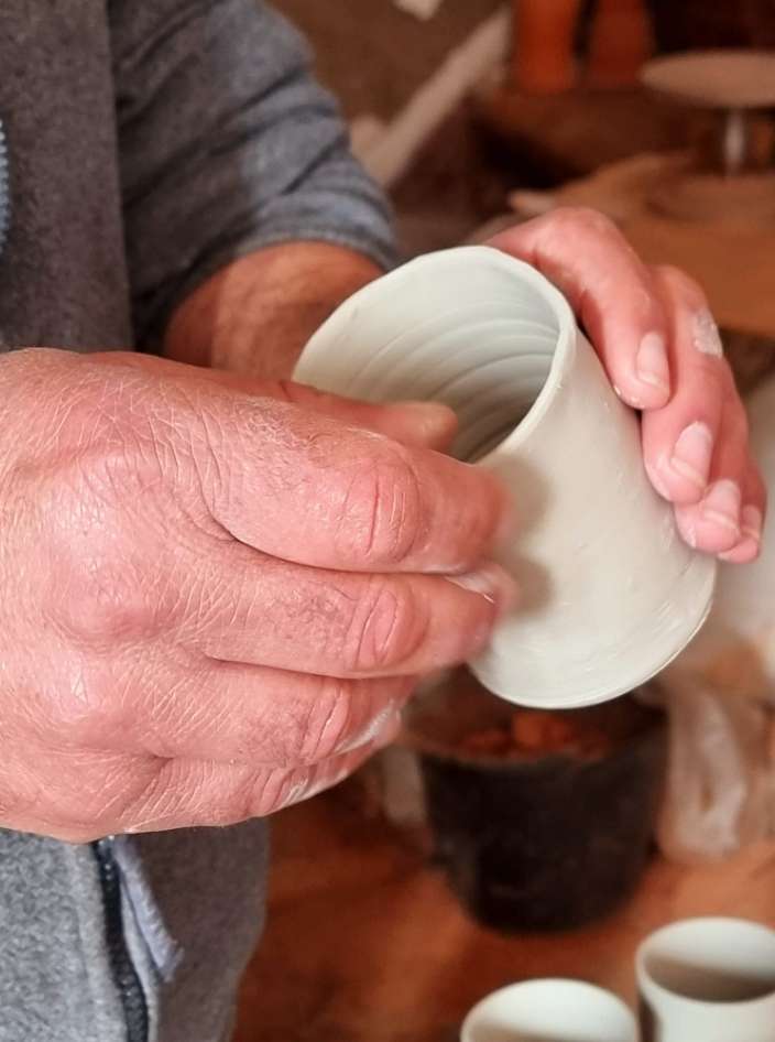 As mãos de um oleiro a moldar um jarro na roda