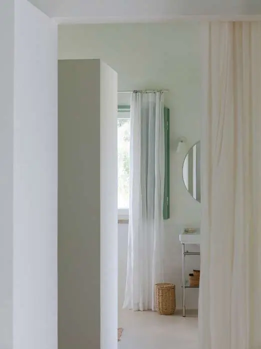 Uma casa de banho para lá de uma cortina de linho, vista da porta do quarto