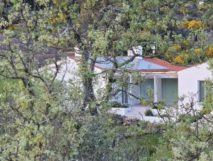 A Casa Esteva entre as árvores, as portadas verdes abertas para a encosta